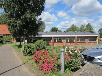 Ringgården set fra indkørslen med blomster i forgrunden